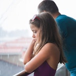 Girl being sad by her father standing on a balcony during the rain on vacation. A dad confessed on R...
