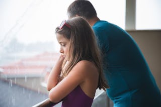 Girl being sad by her father standing on a balcony during the rain on vacation. A dad confessed on R...