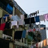 Clean sweaters, trousers and T-shirts hang on a rope outside on a sunny summer day, against a blue s...