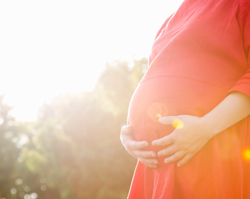 An expecting mother holding her stomach in the park