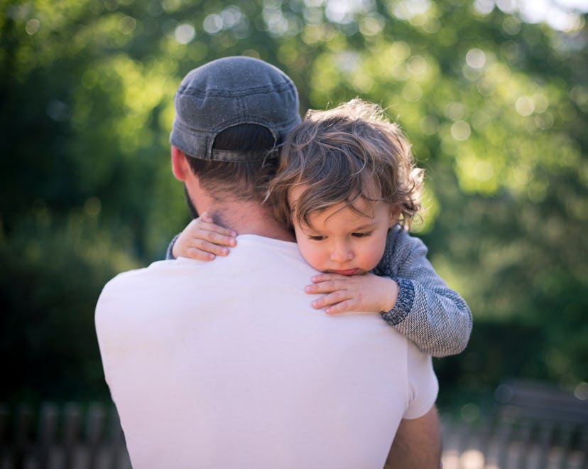 Dad snuggling a toddler in an article about in-laws don't help with grandchildren