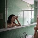 Teenage girl looking at reflection in mirror with hand on the face