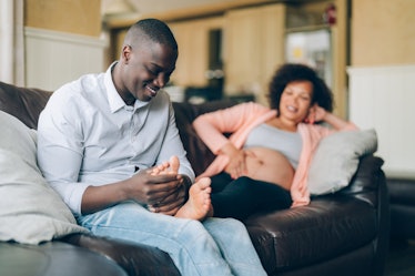Pregnant woman on the couch enjoys a massage from her husband.