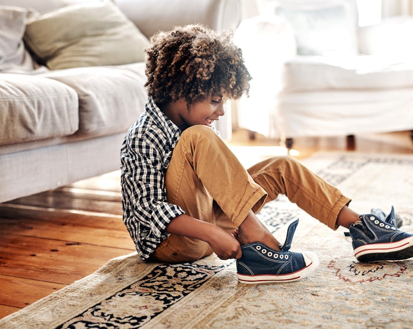 Shot of a determined young little boy trying to put on his shoes getting ready for school in a round...