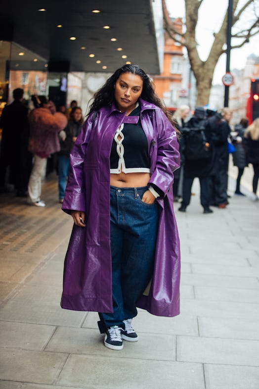 Paloma Elsesser wears a purple leather trench coat, black cropped cardigan, blue jeans, and black Pu…