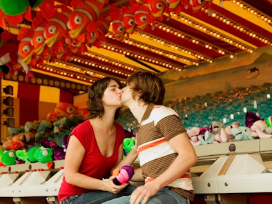 A young couple kisses at a carnival on the most romantic day in November 2022.