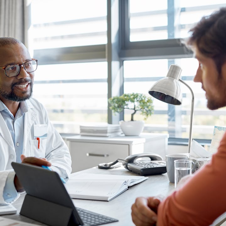 Doctor discussing with man over digital tablet. California just introduced new legislation that aims...