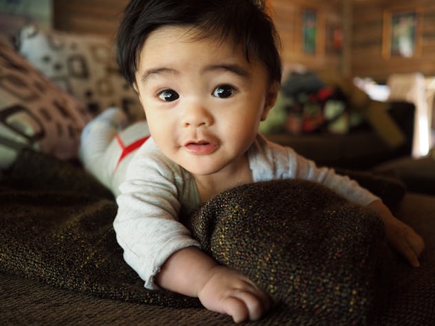 Baby boy on sofa (with pillows and throw blanket) in a log cabin, staring at camera in a round up of...