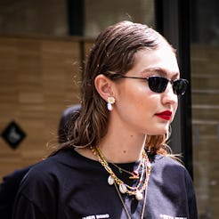 gigi hadid wearing sunglasses with a black t-shirt and a shell necklace