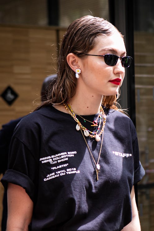 gigi hadid wearing sunglasses with a black t-shirt and a shell necklace
