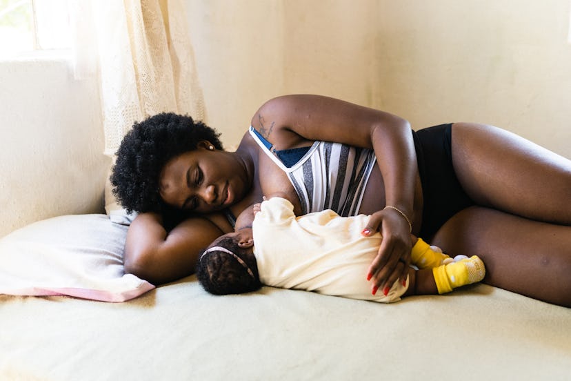 Black mother breastfeeding in bed