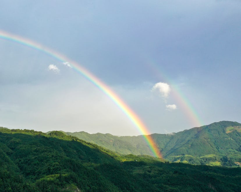 a double rainbow against a blue sky in an article about the term double rainbow baby and what it mea...