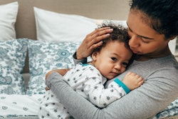 mom snuggling her baby in an article about what to do when your baby sounds congested by has no mucu...
