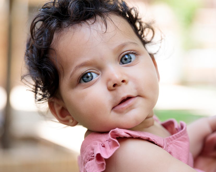 Little girl with blue eyes and curly hair with a disney name looks at the camera