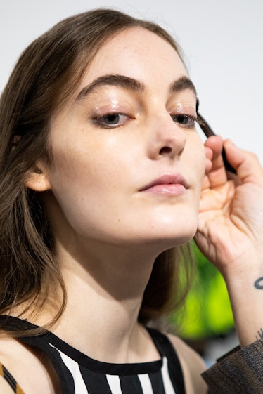 MILAN, ITALY - SEPTEMBER 27: A make up artist does the final touch  of gel eyebrow during the line u...