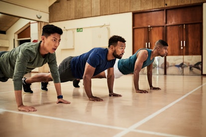 Three men plank together at a gym.