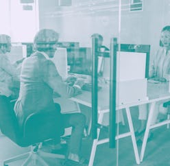 Shot of call center operators working in the office. The view is through glass.