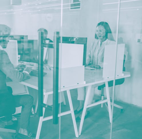 Shot of call center operators working in the office. The view is through glass.