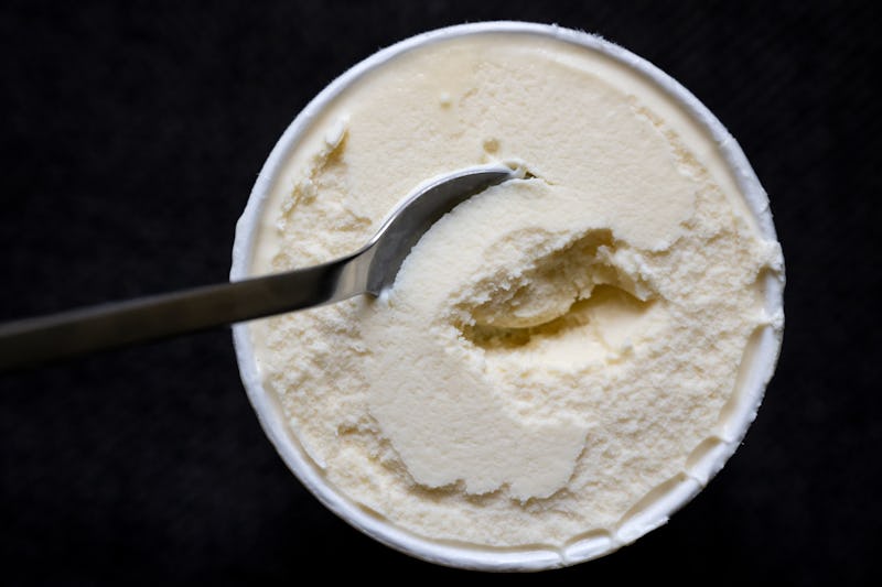 14 July 2022, Bavaria, Munich: A spoon is stuck in a cup of vanilla ice cream. The manufacturer Gene...