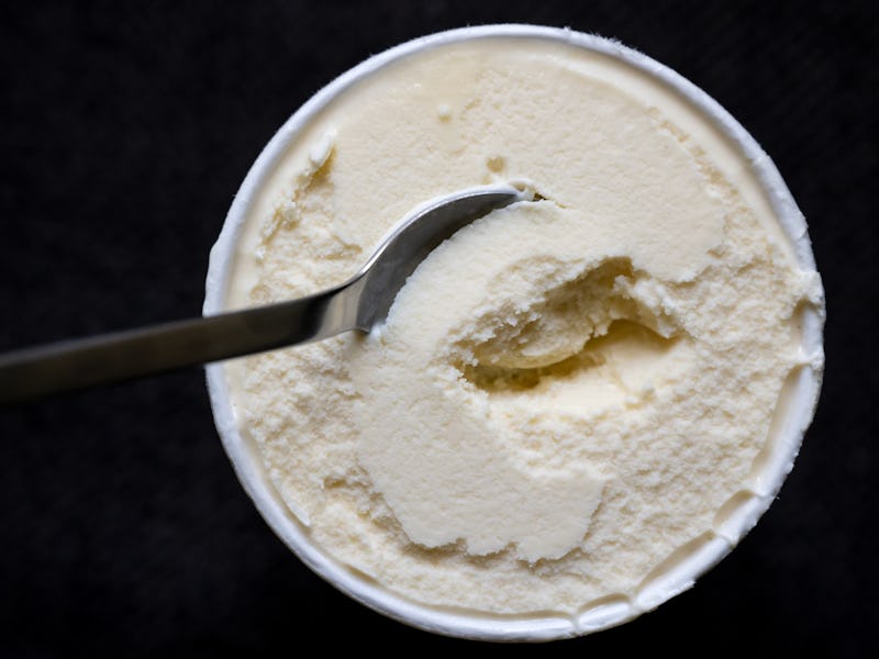 14 July 2022, Bavaria, Munich: A spoon is stuck in a cup of vanilla ice cream. The manufacturer Gene...
