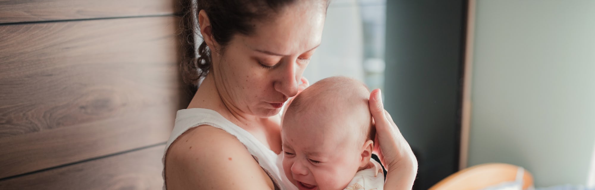 Nervous baby boy shouting in his mother's hands at home