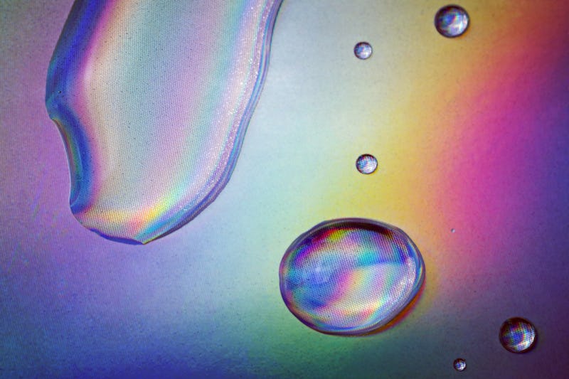 Drops of clear fluid on holographic paper