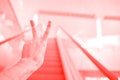 a person climbing an escalator while holding up two fingers in a building