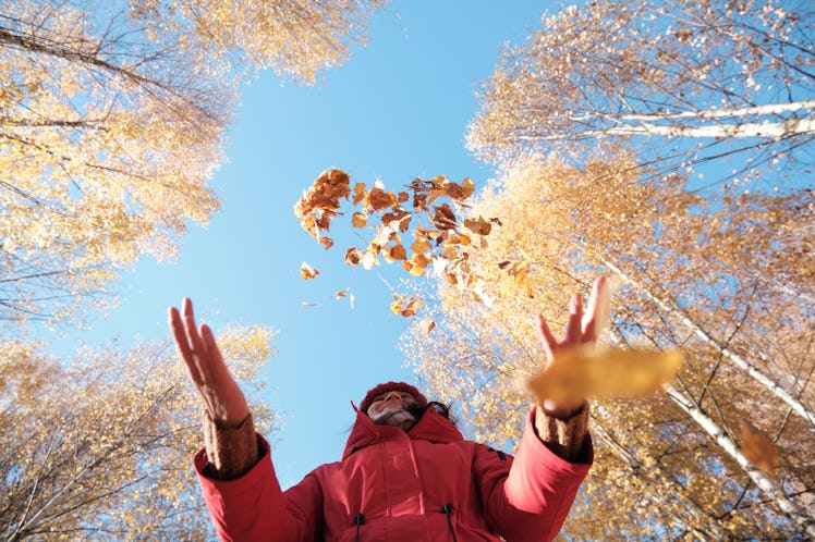 A woman embraces the falling leaves and says hello September with one of these September quotes.