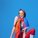 Cheerful fit homosexual woman in bra holding colorful rainbow LGBT flag against blue background in l...