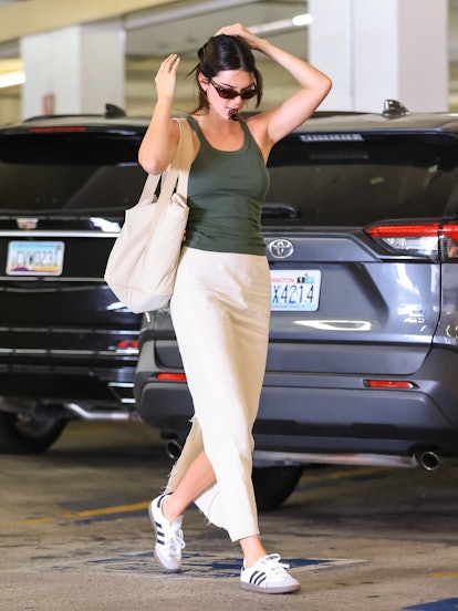 Kendall Jenner wearing a dark green tank top with a cream maxi skirt and white Adidas Samba sneakers