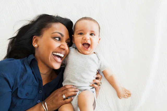A mum holding her newborn baby in her arms, while both have big smiles.