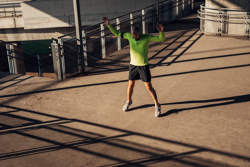 A man doing jumping jacks outside.