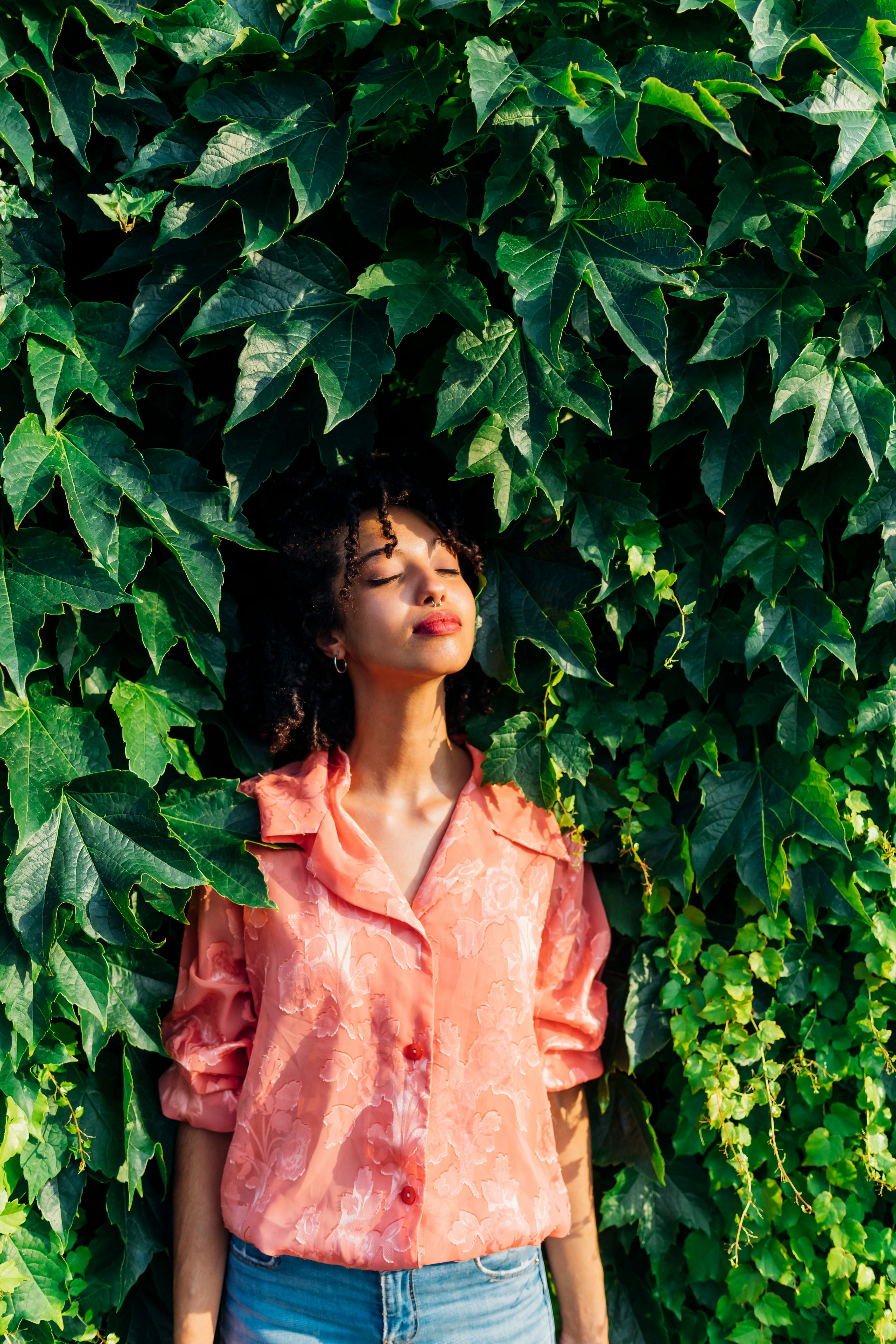 Young woman closing her eyes in front of a plant backdrop. Uranus retrograde arrives on Aug. 24 in h...