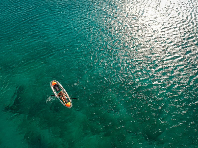 Woman paddling crystal kayak from above