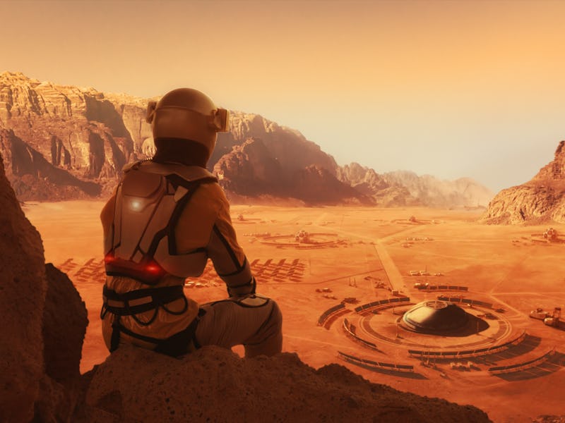 Sitting alone and looking at a Mars space outpost or an alien colony in arid red desert. NASA Public...