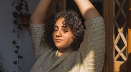 young woman stretches her arms up as she reflects on how september 2022 will affect her sign the lea...