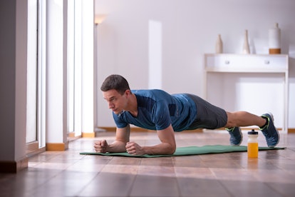 Young man exercising in plank position at home.