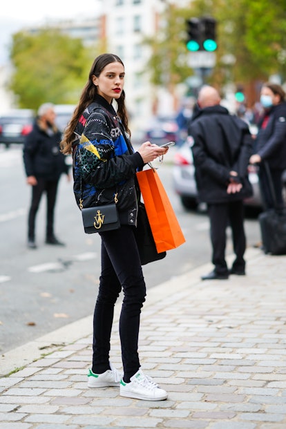 PARIS, FRANCE - OCTOBER 03: A model wears a blue and black colored bomber jacket, a black leather JW...