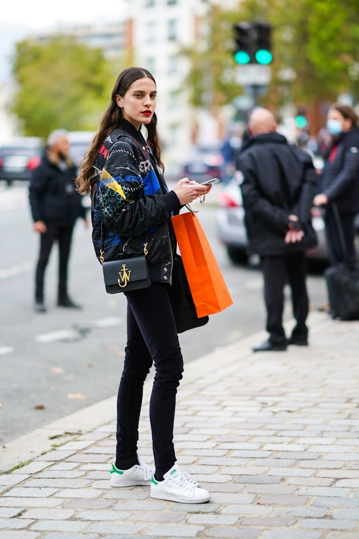 PARIS, FRANCE - OCTOBER 03: A model wears a blue and black colored bomber jacket, a black leather JW...