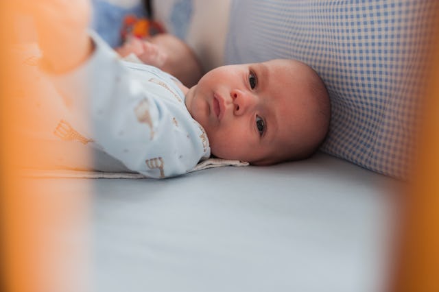 Young serious baby lying down in a crib