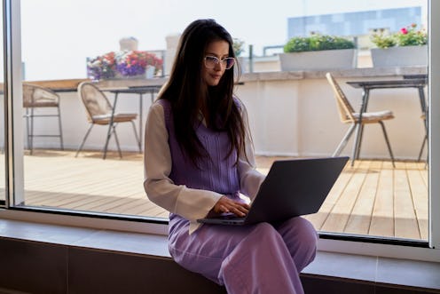 Blogger woman sitting in restaurant while writing the next article of her blog, beautiful sunny summ...