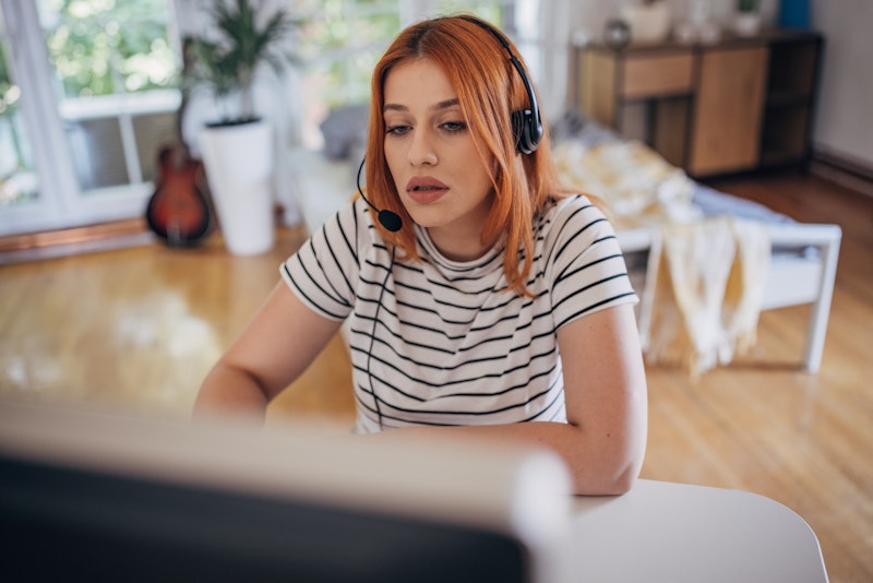 One woman, female university student with headset sitting in her home office, she is using computer.