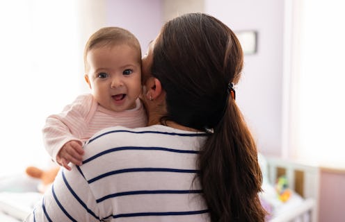 Portrait of a beautiful baby smiling while her mother is carrying her at home - lifestyle concepts