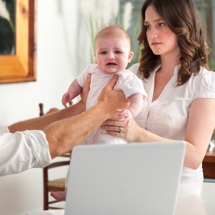 A man hands off a baby to his wife in a prime example of default parent syndrome.