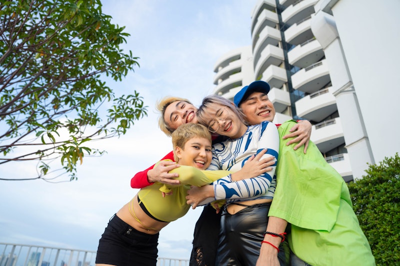 Young Asians LGBTQ+ sharing a laugh and taking selfie together during the evening sunset on rooftop ...