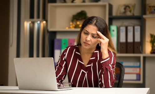 Concerned businesswoman thinking for a solution to her problems while using laptop at home