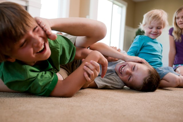 Siblings laughing and play-fighting on the living room floor before the first day of school 