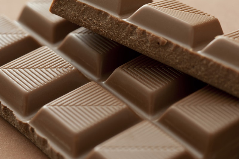 Close up on squares of delicious milk chocolate with broken texture and lines for snacking or cookin...