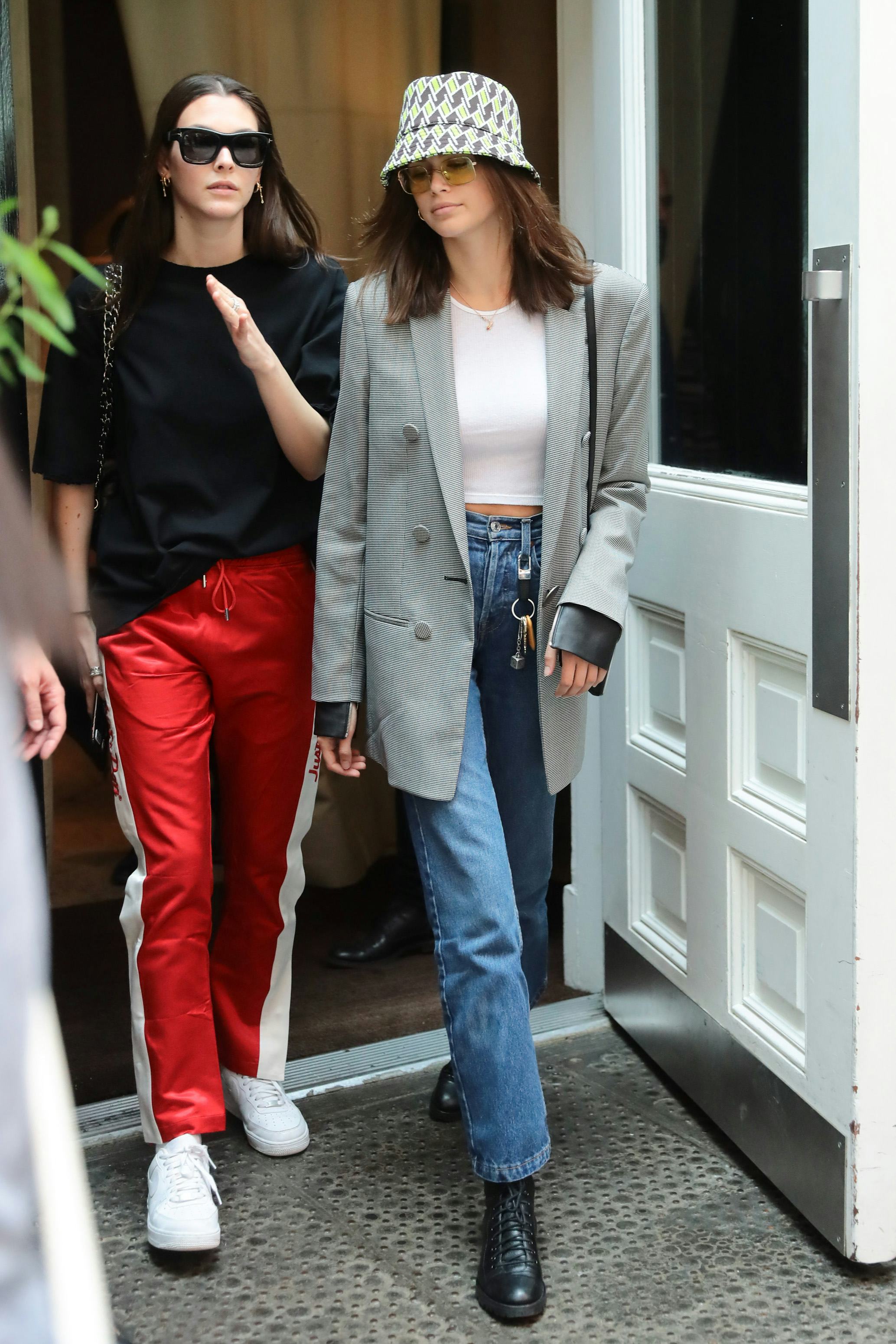 Kaia Gerber wears a bucket hat with a blazer, jeans, and lace-up leather boots