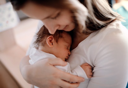 A young woman cuddling her new baby in an article about how long does a cold last?